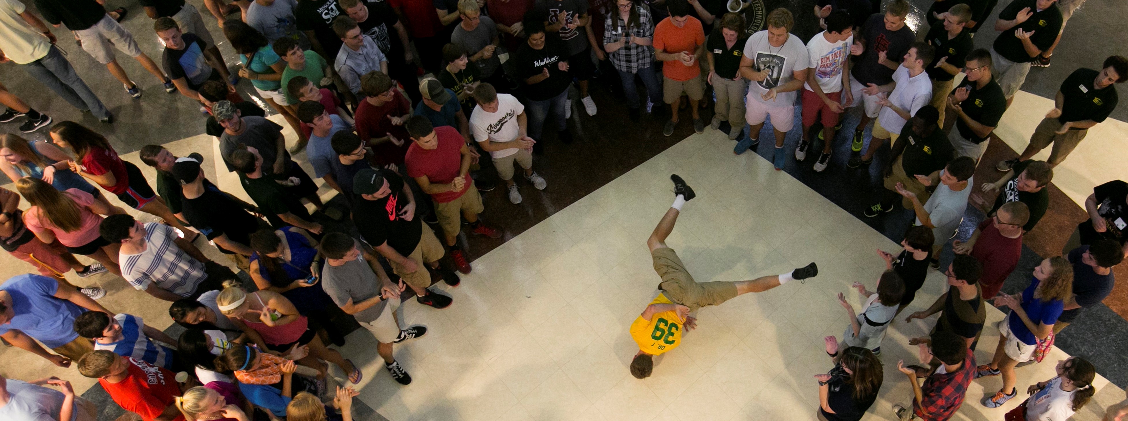 Students gathered around another student dancing